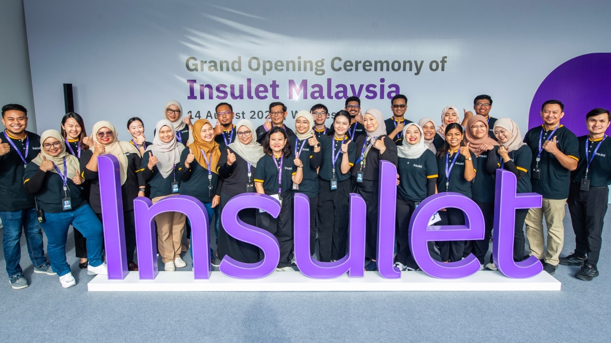 Insulet employees in Malaysia standing behind a purple Insulet sign