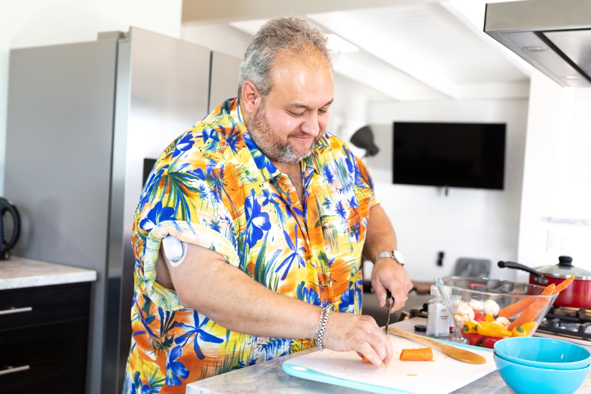 A man showing his Omnipod while prepping a meal in his kitchen