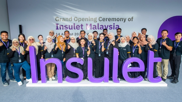 Insulet employees in Malaysia standing behind a purple Insulet sign