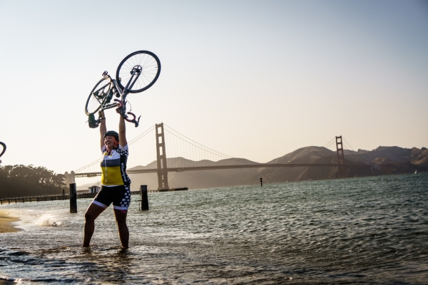 A woman holding her bike above her head in celebration