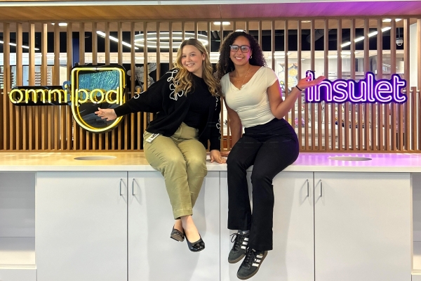 Two students sitting on a table in the cafeteria room at Insulet