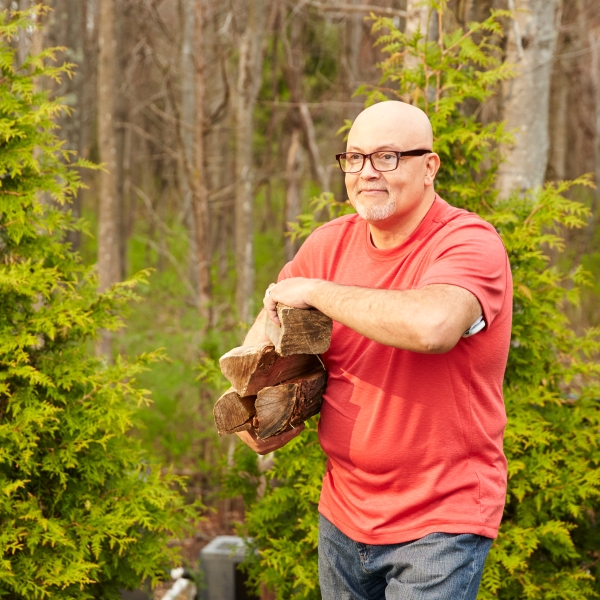 A man carrying wood in his yard
