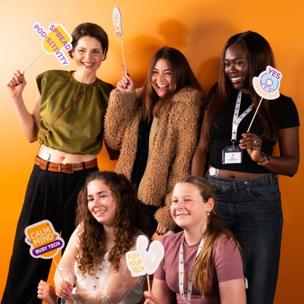 Group of Insulet customers standing in front of a photo booth and mango backdrop